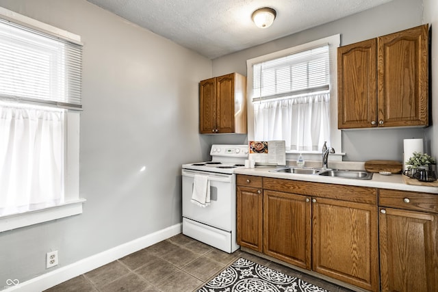 kitchen with a sink, brown cabinetry, baseboards, and white electric stove