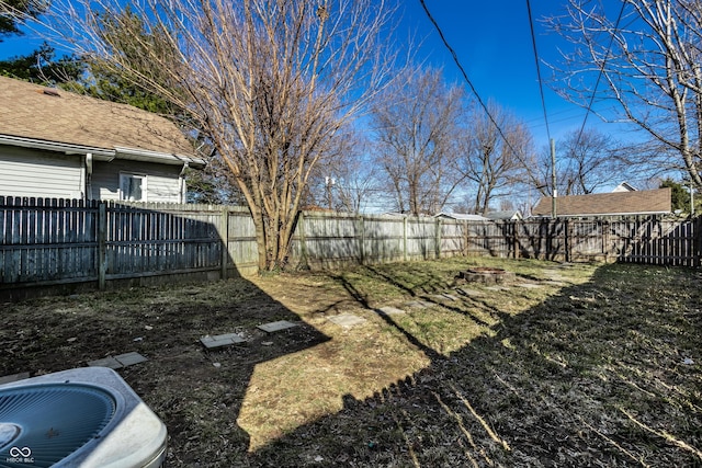 view of yard with central AC unit, a fenced backyard, and a fire pit