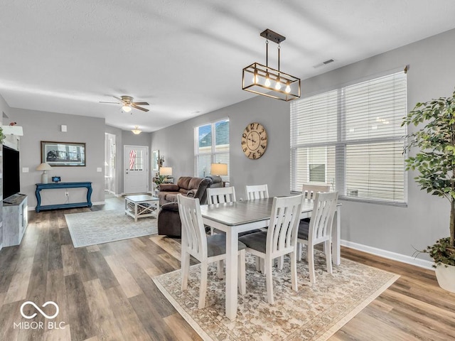 dining area with wood finished floors, a ceiling fan, and baseboards