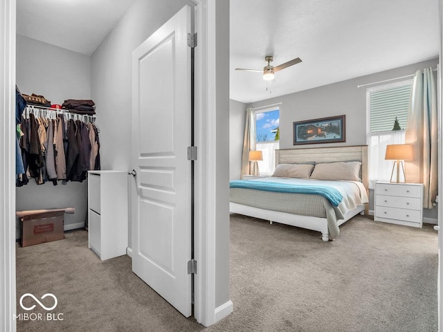 bedroom with a closet, light carpet, ceiling fan, and baseboards