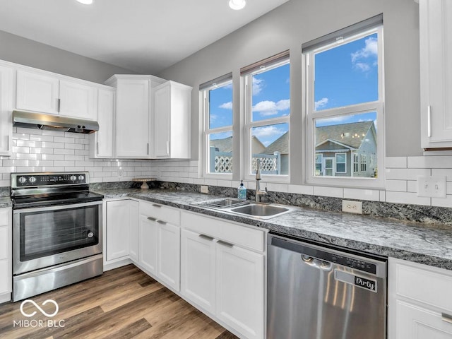 kitchen with appliances with stainless steel finishes, white cabinetry, a sink, and under cabinet range hood