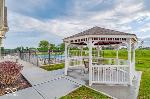 view of patio / terrace with a gazebo, fence, and a community pool