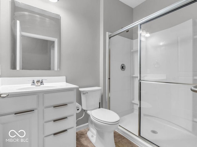 full bath with toilet, vanity, baseboards, a shower stall, and tile patterned floors