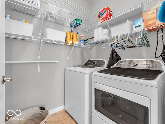 clothes washing area featuring laundry area, light tile patterned floors, baseboards, and separate washer and dryer