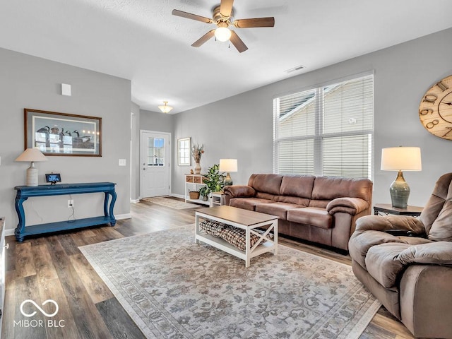 living room featuring dark wood-style floors, visible vents, ceiling fan, and baseboards