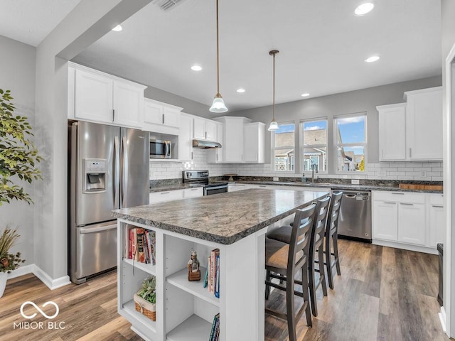 kitchen with stainless steel appliances, a kitchen island, and white cabinetry