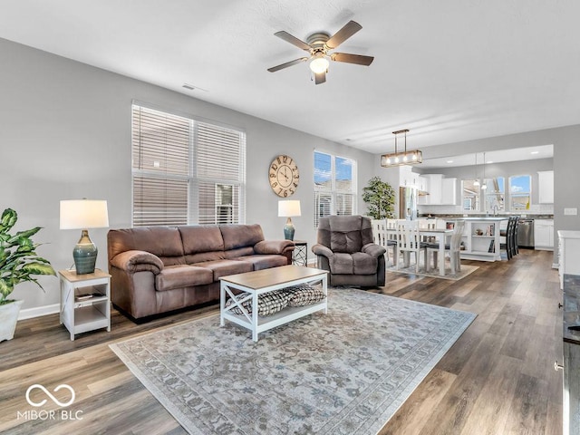 living room with a ceiling fan, wood finished floors, visible vents, and baseboards