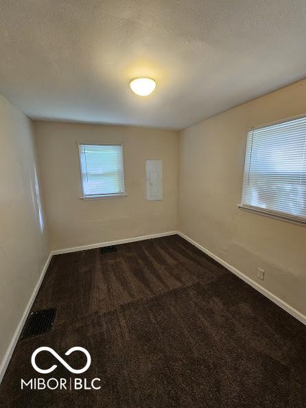 spare room with dark carpet and baseboards