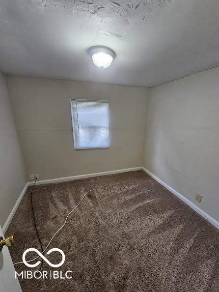 unfurnished room featuring carpet and baseboards