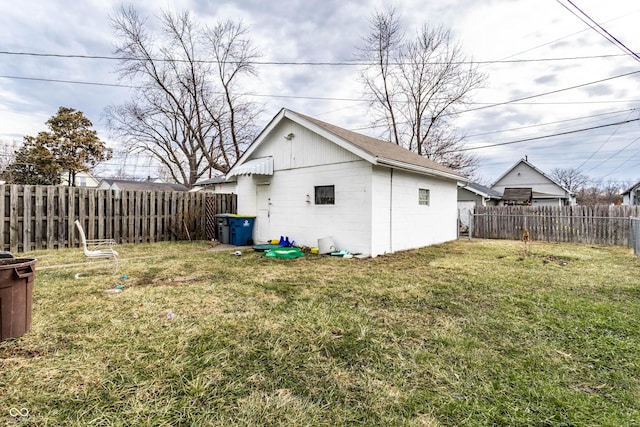 exterior space with a fenced backyard, concrete block siding, and a lawn