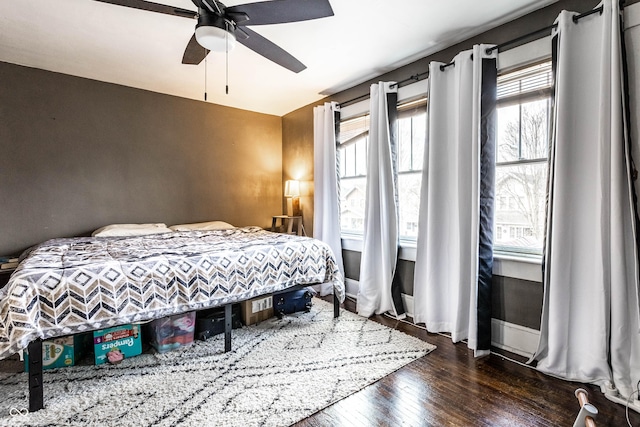 bedroom with a ceiling fan, dark wood-style flooring, and baseboards