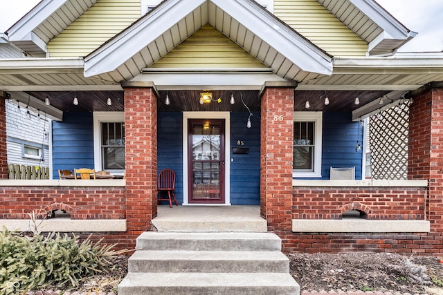 entrance to property with a porch and brick siding