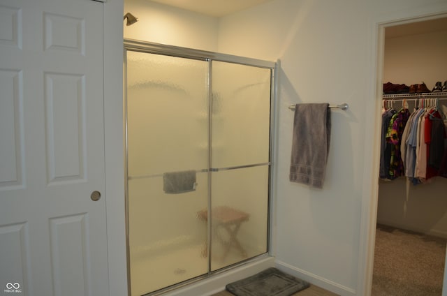 full bath with baseboards, a walk in closet, and a shower stall