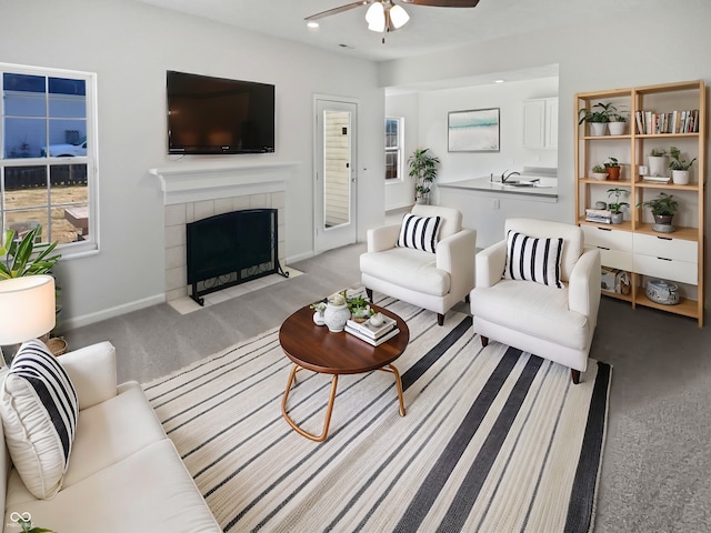 living room with ceiling fan, a fireplace, baseboards, and light colored carpet