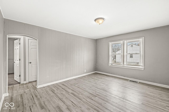 empty room featuring baseboards, visible vents, and wood finished floors