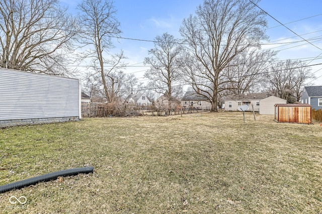 view of yard featuring an outbuilding, fence, and a storage shed