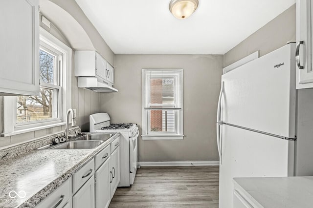 kitchen featuring under cabinet range hood, white appliances, a sink, and a healthy amount of sunlight