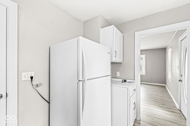 kitchen featuring baseboards, white cabinets, light countertops, freestanding refrigerator, and light wood finished floors