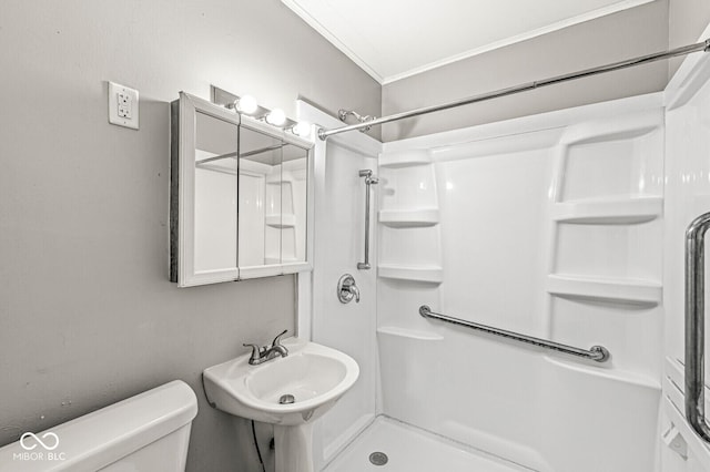 bathroom with a shower, crown molding, a sink, and toilet