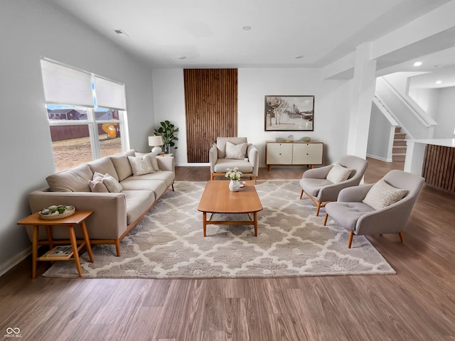 living area with stairs, baseboards, and wood finished floors