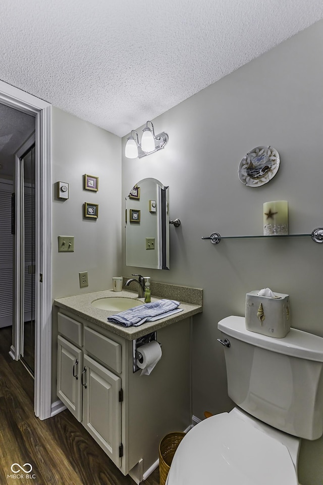 bathroom with toilet, a textured ceiling, vanity, and wood finished floors