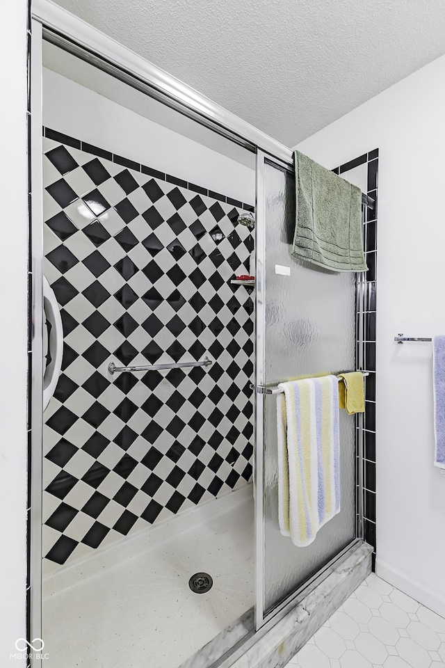 bathroom with a textured ceiling and a tile shower