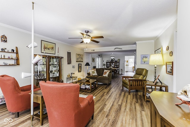 living area with a ceiling fan, a textured ceiling, ornamental molding, and wood finished floors