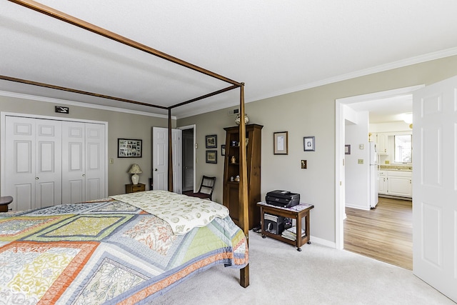 bedroom with crown molding, a closet, freestanding refrigerator, light carpet, and baseboards