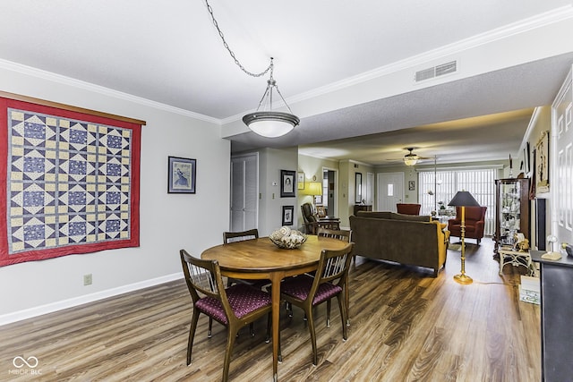 dining room with ornamental molding, visible vents, baseboards, and wood finished floors