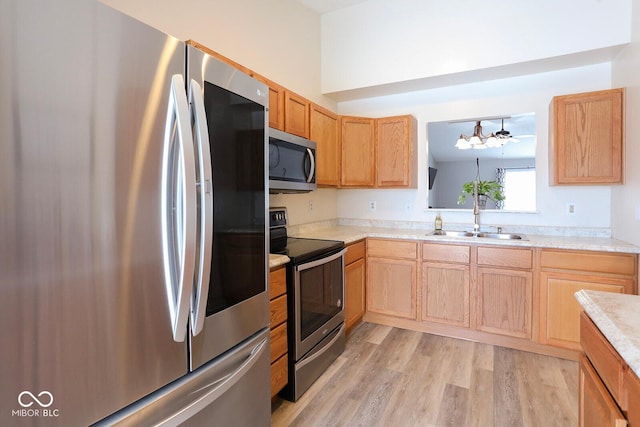 kitchen featuring light brown cabinets, stainless steel appliances, a sink, light countertops, and light wood-type flooring