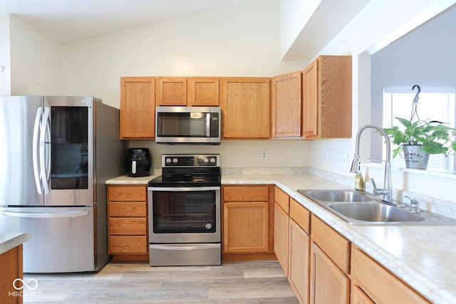 kitchen featuring lofted ceiling, appliances with stainless steel finishes, light countertops, and a sink