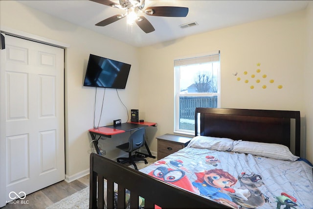 bedroom with baseboards, ceiling fan, visible vents, and wood finished floors