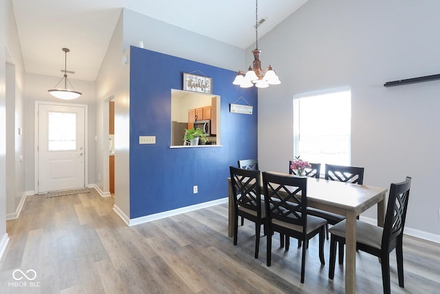 dining area featuring high vaulted ceiling, baseboards, a chandelier, and wood finished floors