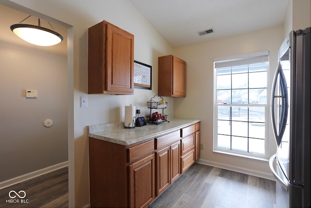 kitchen with visible vents, light countertops, a wealth of natural light, freestanding refrigerator, and brown cabinetry