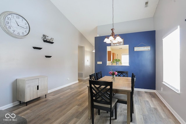 dining space with high vaulted ceiling, baseboards, visible vents, and wood finished floors