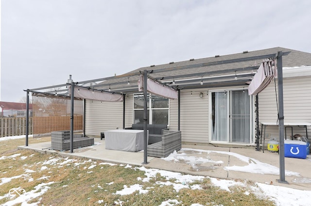 snow covered rear of property featuring a patio area, fence, and a pergola