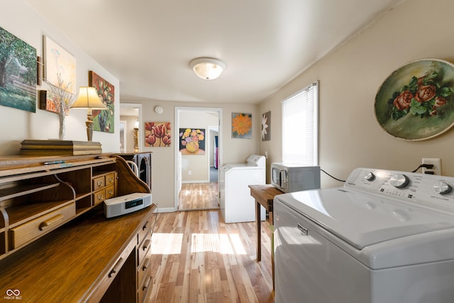 washroom with light wood-style floors, washing machine and dryer, laundry area, and baseboards