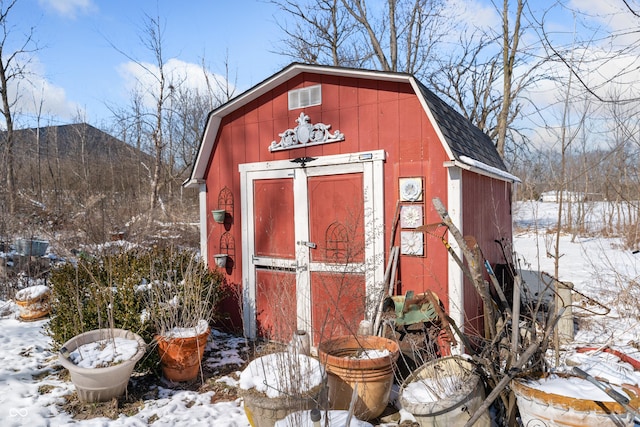 snow covered structure featuring an outdoor structure and a storage unit