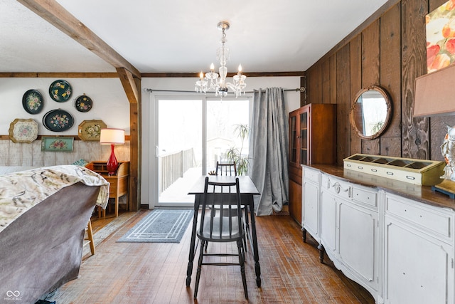 kitchen featuring light wood finished floors, white cabinets, dark countertops, pendant lighting, and a notable chandelier