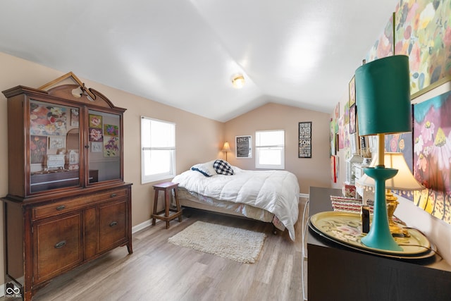 bedroom with lofted ceiling, baseboards, multiple windows, and light wood finished floors