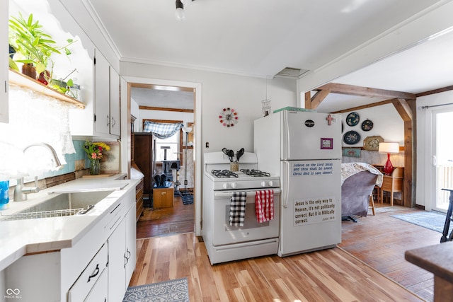 kitchen with light countertops, light wood-style flooring, white cabinets, a sink, and white appliances