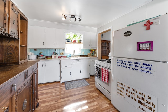 kitchen with tasteful backsplash, white appliances, white cabinets, and a sink