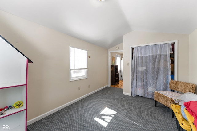 interior space featuring lofted ceiling, baseboards, and dark colored carpet