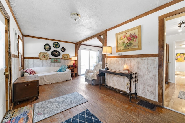 bedroom with crown molding, visible vents, hardwood / wood-style floors, and wainscoting