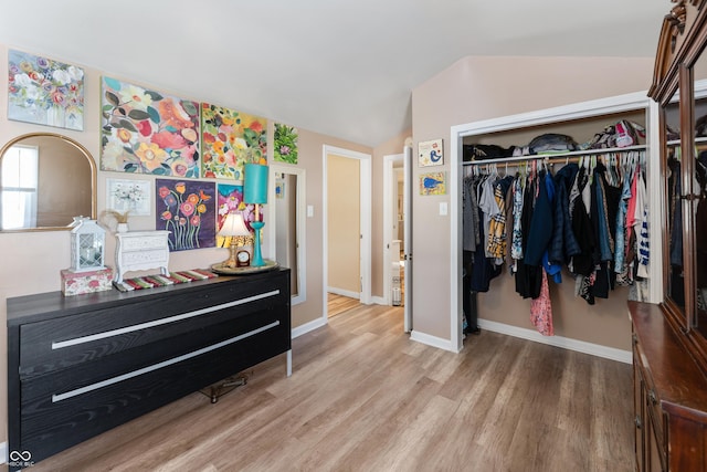 bedroom with vaulted ceiling, a closet, wood finished floors, and baseboards