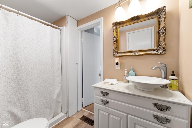 bathroom with visible vents, toilet, vanity, wood finished floors, and a shower with curtain