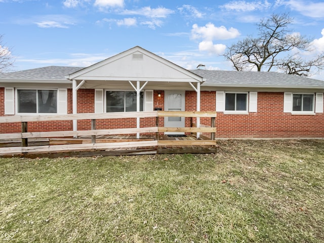 ranch-style home featuring brick siding, a front lawn, and roof with shingles