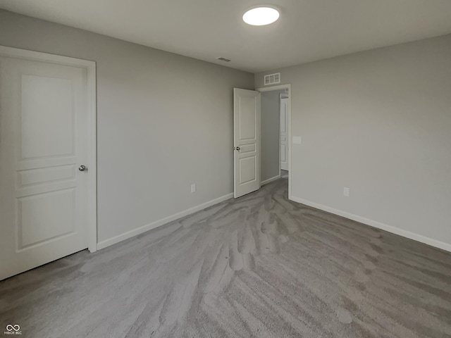 empty room with carpet flooring, visible vents, and baseboards