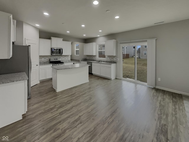 kitchen featuring white cabinets, decorative backsplash, dark wood-style floors, a kitchen island, and stainless steel appliances