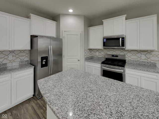 kitchen featuring appliances with stainless steel finishes, white cabinets, decorative backsplash, and wood finished floors